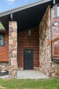 a front door of a log cabin with a black door at Honeybear Hideaways - Luxurious Modern 7BR Cabin with Indoor Pool, Game Room, Hot Tub & Fireplace in Sevierville