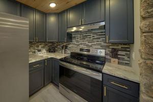 a kitchen with black cabinets and a stove top oven at Honeybear Hideaways - Luxurious Modern 7BR Cabin with Indoor Pool, Game Room, Hot Tub & Fireplace in Sevierville