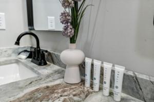 a white vase with flowers in it next to a sink at Honeybear Hideaways - Luxurious Modern 7BR Cabin with Indoor Pool, Game Room, Hot Tub & Fireplace in Sevierville