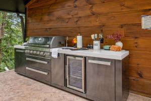 an outdoor kitchen with a stove and a counter at Honeybear Hideaways - Luxurious Modern 7BR Cabin with Indoor Pool, Game Room, Hot Tub & Fireplace in Sevierville