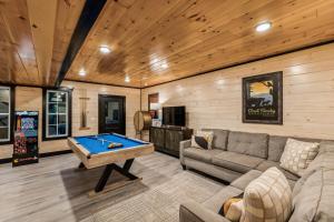 a living room with a couch and a pool table at Honeybear Hideaways - Luxurious Modern 7BR Cabin with Indoor Pool, Game Room, Hot Tub & Fireplace in Sevierville
