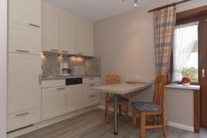 a kitchen with white cabinets and a table and chairs at Schleswig-Holstein Whg 01 EG li in Nieblum