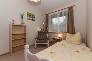 a bedroom with a bed and a chair and a window at Schleswig-Holstein Whg 01 EG li in Nieblum