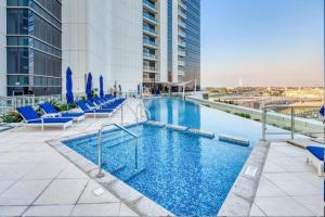 a pool on the roof of a building with chairs and umbrellas at Avani Palm View - Bright Two Bedroom with Sea View in Dubai