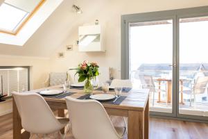 ein Esszimmer mit einem Holztisch und weißen Stühlen in der Unterkunft Ostsee - Appartement Nr 19 "Sonnenzauber" im Strand Resort in Heiligenhafen