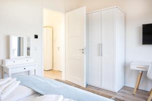 ein weißes Schlafzimmer mit einem Schrank und einem Bett in der Unterkunft Ostsee - Appartement Nr 19 "Sonnenzauber" im Strand Resort in Heiligenhafen + 17 Fotos