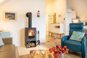 ein Wohnzimmer mit einem Kamin und einem blauen Stuhl in der Unterkunft Ostsee - Appartement Nr 19 "Sonnenzauber" im Strand Resort in Heiligenhafen