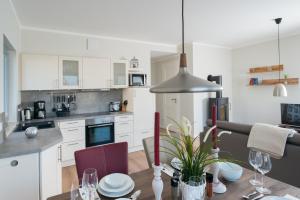 eine Küche mit weißen Schränken und einem Tisch mit Stühlen in der Unterkunft Ostsee - Appartement Nr 181 "Uferschwalbe" im Strand Resort in Heiligenhafen