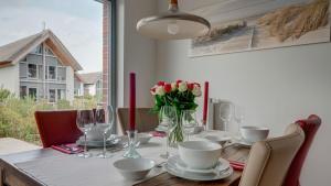 ein Esstisch mit einer Vase mit Blumen darauf in der Unterkunft Ostsee - Appartement Nr 181 "Uferschwalbe" im Strand Resort in Heiligenhafen