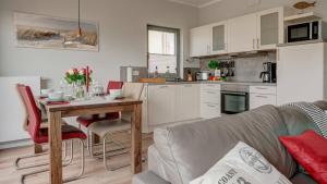 eine Küche und ein Wohnzimmer mit einem Tisch und einer Couch in der Unterkunft Ostsee - Appartement Nr 181 "Uferschwalbe" im Strand Resort in Heiligenhafen + 15 Fotos