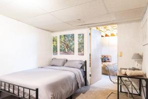 a white bedroom with a bed and a table at Semi Finished Basement with Pvt Bath Pvt Living Rm and pull out couch in Livonia