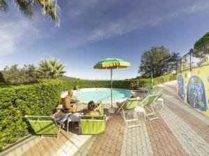 a man and a dog sitting under an umbrella next to a pool at Appartements mit Veranda, Andora in Marina di Andora