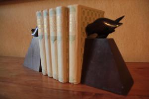 Ein Stapel Bücher auf einem Tisch mit einer Katzenstatue in der Unterkunft Anges Gardiens in Villeneuve-lès-Béziers