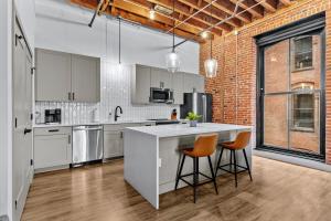 Una cocina con gabinetes blancos y una encimera con taburetes. en Stunning 5 Star Stay! Guest Favorite with River View, en Saint Louis