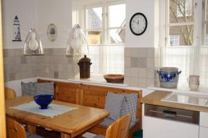 a kitchen with a table and a clock on the wall at Hüs an den Salzwiesen in Borgsum +15 photos