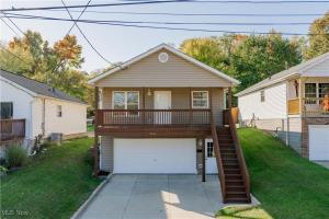 a house with a deck and a garage at Comfort Awaits at Cozy Get Away - Dog Friendly in Akron
