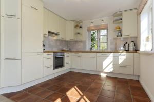 a kitchen with white cabinets and a brown tile floor at Haus Strandburg in Wyk auf Föhr