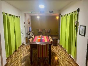 a living room with a table with green curtains at Hostel Alelí in Cafayate