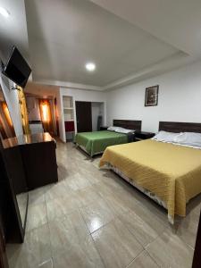 a hotel room with two beds and a flat screen tv at Hostal Monterrico in Monterrico