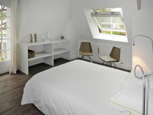 a white bedroom with a bed and two chairs at Holiday Home in Carnac near Sandy Beach in Carnac