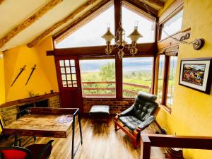 a living room with a chair and a table and windows at Varsovia, casa de madera biblioteca in Guatavita