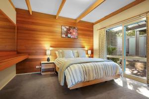 1 dormitorio con paredes de madera, 1 cama y ventana en Pelicans, en Rye