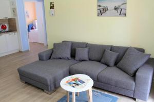 a living room with a gray couch and a table at Seeschwalbe App 34 in Neuhaus