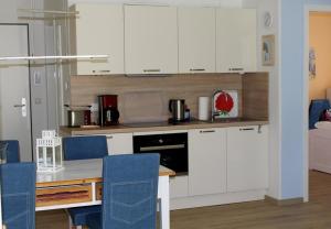 a kitchen with white cabinets and a table with blue chairs at Seeschwalbe App 34 in Neuhaus
