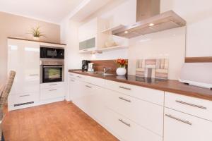M5 Bungalow - Apartmenthaus Marienburger Str 4 - FERIENDOMIZIL HOLLICH في غروميتز: مطبخ بدولاب بيضاء وأرضية خشبية