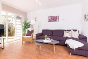 M5 Bungalow - Apartmenthaus Marienburger Str 4 - FERIENDOMIZIL HOLLICH في غروميتز: غرفة معيشة مع أريكة أرجوانية وطاولة +17 صورة