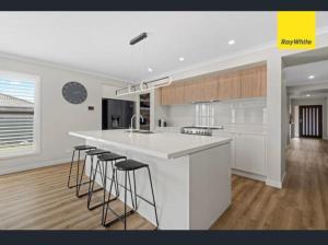 a kitchen with a white counter and bar stools at Serenity in Melton South