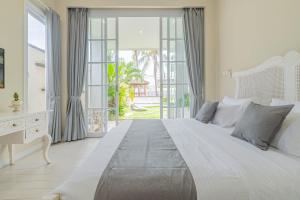 Un dormitorio blanco con una cama grande y un escritorio. en The Beautiful villa, Casa Sara, en Canggu 65 fotos más