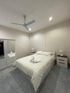 a white bedroom with a bed and a ceiling fan at Your Lifestyle Guesthouse in Patong Beach