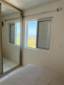 a bedroom with a bed and a large window at Apartamento aconchegante Mar Grosso in Laguna