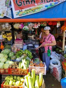a woman standing in front of a market with fruits and vegetables at Hondelz Budget Homestay in Busuanga