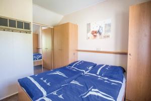 a bedroom with a bed with a blue comforter at Ferienhaus Paulchen im Müritz Seepark in Röbel