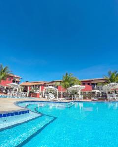a large swimming pool with chairs and umbrellas at AREIA DE TAPERAPUAN - 200 MTS da PRAIA - ORLA NORTE in Porto Seguro