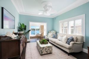 Una sala de estar con un sofá y un ventilador de techo. en Whitesands Beach House Cronulla, en Cronulla