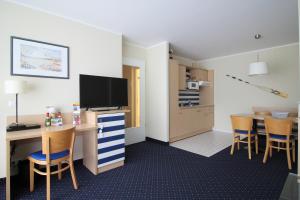 a room with a kitchen and a desk with a television at Möwe App 510 in Zingst