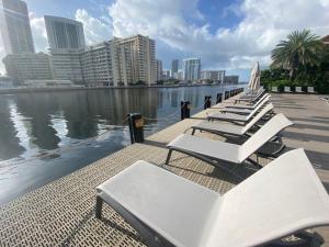 a row of white lounge chairs next to a body of water at Miami Beach Cozy 1B withe Pool and Beach Service1507 in Hallandale Beach