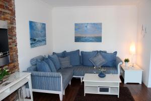 ein Wohnzimmer mit einer blauen Couch und einem Tisch in der Unterkunft LANDHAUS AM HAFEN im OG in Heiligenhafen