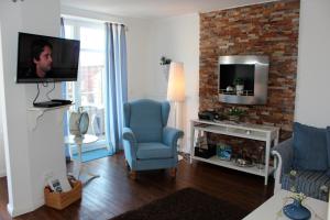 ein Wohnzimmer mit einem TV und einem blauen Stuhl in der Unterkunft LANDHAUS AM HAFEN im OG in Heiligenhafen