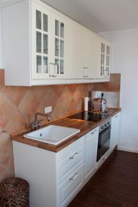 eine Küche mit weißen Schränken und einer Spüle in der Unterkunft LANDHAUS AM HAFEN im OG in Heiligenhafen