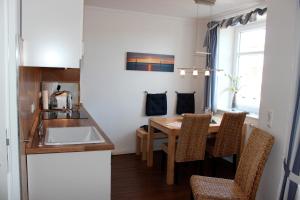 eine kleine Küche mit Tisch und Spüle in der Unterkunft LANDHAUS AM HAFEN im OG in Heiligenhafen