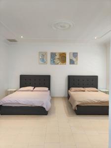 two beds in a room with white walls at Pangkor Island Seaside @ 4 rooms Homestay in Pasir Bogak