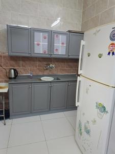 a kitchen with gray cabinets and a white refrigerator at شقة مفروشة in Al Baha