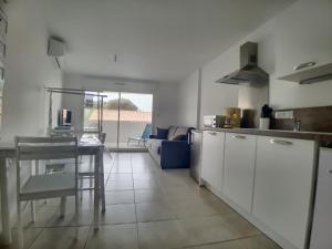 a kitchen with white cabinets and a table in it at Studio 4 pers climatisé avec parking, à 100m de la mer - FR-1-475-174 in Saintes-Maries-de-la-Mer
