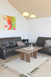 sala de estar con mesa y sofás de cuero en "Ferienhaus I - Hof Westensee", en Grömitz