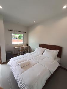 a bedroom with a large bed with white sheets and pillows at Good Nine Resort in Ban Lam Kaen