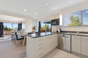 a kitchen with white cabinets and a dining room with a table at Top Spot Rotorua in Rotorua +17 photos